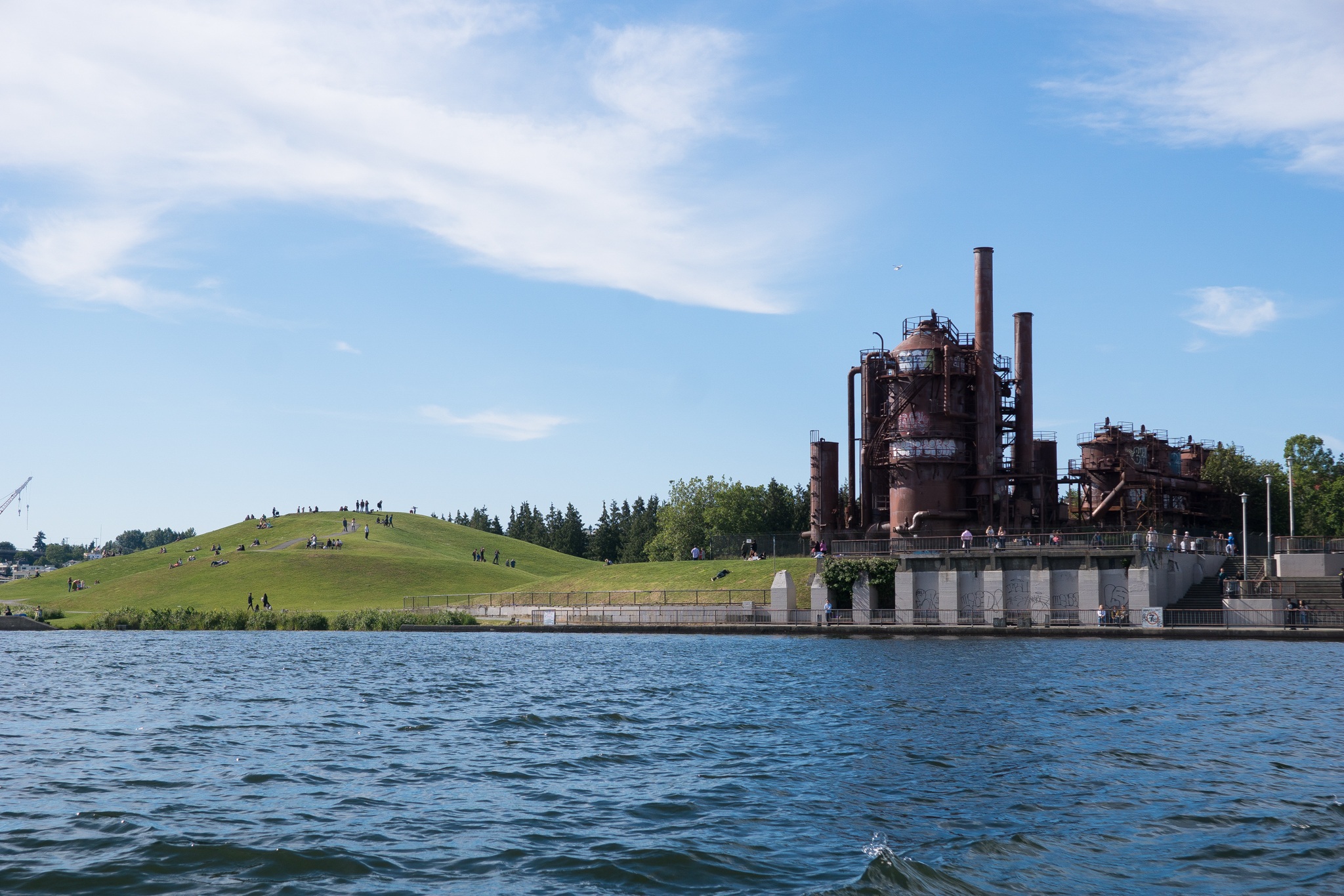 Families enjoying a sunny day at Gas Works Park in Seattle, with children playing on the open green spaces and the city skyline in the background.